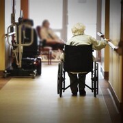 Une dame dans un fauteuil roulant dans le couloir d'un CHSLD.