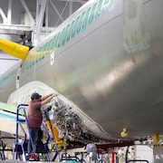 Dans un entrepôt, une personne travaille sur un avion.