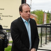 Alain Bellefeuille, menotté, marche vers le palais de justice de L'Orignal.