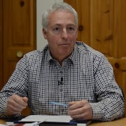 Alain Boisvert à un bureau avec un crayon.