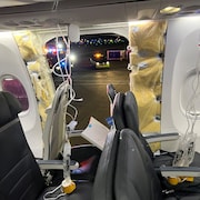 Un trou dans la carlingue de l'avion et un masque à oxygène qui pend.