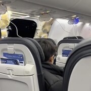 Deux passagers assis dans un avion, non loin d'un trou dans la carlingue de l'avion. 