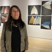 L'artiste Alejandra Basanes devant ses oeuvres dans une salle d'exposition