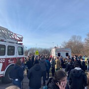 Des dizaines d'élèves à l'extérieur à côté d'un camion de pompier et d'une ambulance.