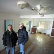 Les deux hommes posent dans la maison qui doit être démolie.