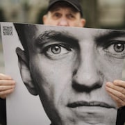 Un homme tient une affiche avec le portrait du leader de l'opposition Alexei Navalny.