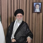 Ali Khamenei pose aux côté du drapeau iranien et d'un portrait de l'ayatollah Rouhollah Khomeini.