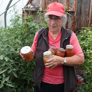 Une femme montre sa serre de tomates.