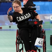 Une femme en fauteuil roulant qui lance une boule. 