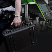 Montage d'une valise à la main d'un enquêteur avec un tramway en arrière-plan.
