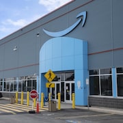 La façade d'un entrepôt avec le logo d'Amazon, un sourire se terminant en flèche.