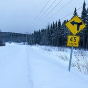 La route enneigée avec un panneau devant.