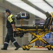 Deux ambulanciers poussent une civière après avoir transporté un patient à l'Hôpital Mount Sinai de Toronto.