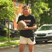 Une adolescente joue au basketball dans un quartier résidentiel.