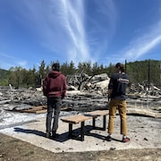 Deux personnes devant les restes brûlés du chalet du Mont Édouard.