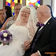 Deux nouveaux mariés, âgés, qui sourient.