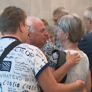 Groupe de personnes à la sortie de la salle d'audience.