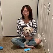 Une femme assise par terre avec un chien sur les genoux.
