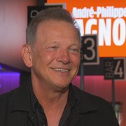 Un homme sourit dans le corridor d'une salle de spectacle. 