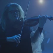 Une femme portant des lunettes et tenant un violon.