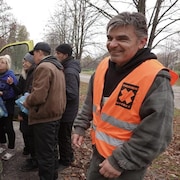 Anthony « Tonko » Ihnat sourit à côté de bénévoles à l'extérieur d'un véhicule.