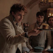 Un homme tient une assiette remplie devant trois autres hommes.