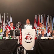 Plusieurs chefs de l'Assemblée des Premières Nations autour d'un podium. 