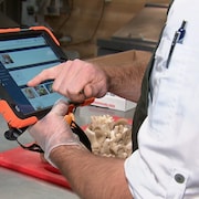 Un cuisinier tient une tablette électronique affichant l'application Octogone. 