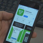 L'application est visible sur le téléphone d'une personne qui tient son cellulaire dans la main.