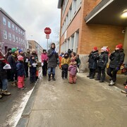Des parents et leurs enfants sont dehors devant des professeurs en grève.