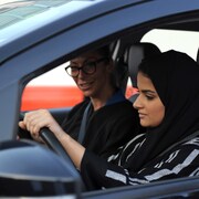 Une femme portant un voile noir est au volant d'une voiture accompagnée d'une autre femme portant des lunettes.