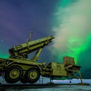 Un engin militaire sous une aurore boréale.