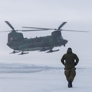 Un homme marche de dos vers un hélicoptère qui s'apprête à se poser au sol durant l'opération militaire Nanook, dans le nord des Territoires du Nord-Ouest, le 1er mars 2025.