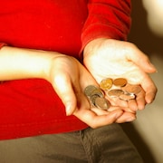 Une femme tient de la menue monnaie dans ses deux mains.
