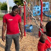 Un homme pousse un bambin sur un balançoire. 