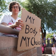 Une femme tient une pancarte sur laquelle on peut lire : « My Body My Choice (Mon corps, mon choix) ».