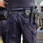 Plan rapproché des armes à feu et des bâtons accrochés au ceinturon que porte un policier de la GRC en service.