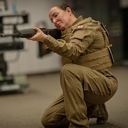 Une soldate en uniforme tient une arme.