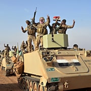 Des soldats irakiens, sur des tanks, font le V de la victoire.