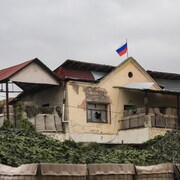 Une maison délabrée avec un drapeau russe. 