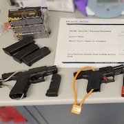 Des armes à feu, des munitions et des chargeurs sont déposés sur une table.