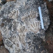 Empreintes de mains et de pieds visibles sur une roche.