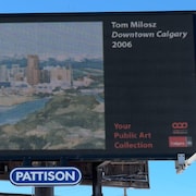 Sur un panneau publicitaire électrique est diffusée la peinture de Tom Milosz intitulée « Dowtown Calgary ».