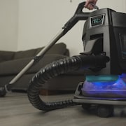 Une personne passe l'aspirateur dans un salon.