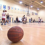 Un ballon de basket sur un plancher de gymnase pendant un match amical.