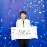 Une femme montre un gros chèque en carton pour illustrer son prix.