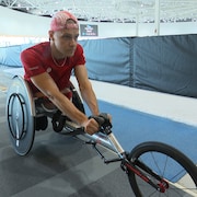 Un homme se pr&eacute;pare &agrave; s'&eacute;lancer sur son fauteuil roulant de course, &agrave; l'int&eacute;rieur.