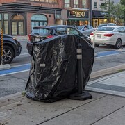 Une poubelle de la ville recouverte d'un sac de poubelle est une des installations de AusterityTO.
