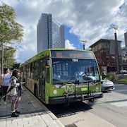 Des usagers s’apprêtent à monter à bord d’un autobus du RTC au centre-ville de Québec en été.