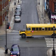 Un autobus scolaire traverse l'intersection de deux rues étroites.